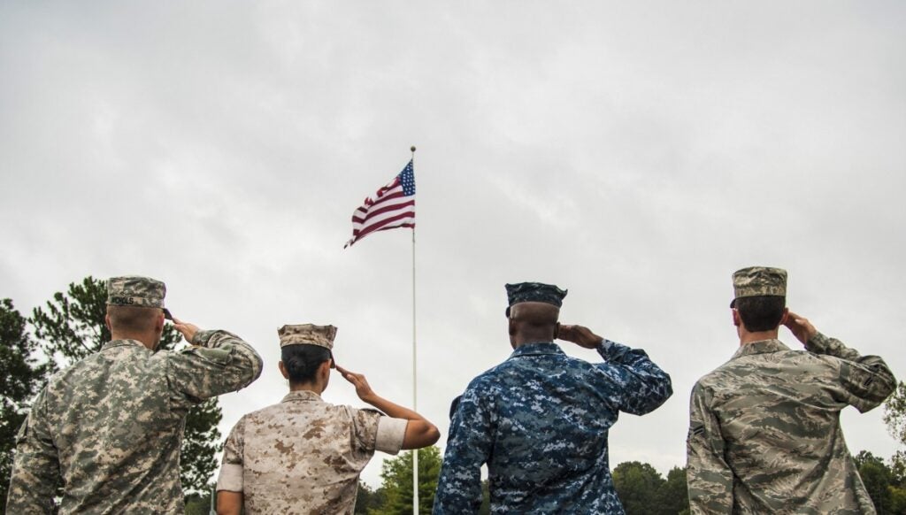 Military personnel saluting the American flag